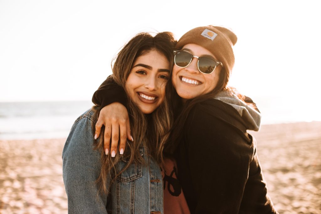 two friends smile together on the beach