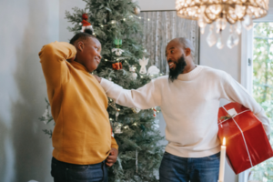 teen and adult male smiling talking to each other inside in front of christmas tree