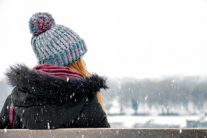 back of girl outside in winter wearing hat and jacket looking into the distance