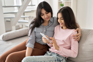 Women and teen sitting on couch looking at phone