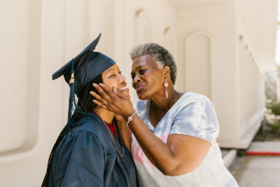 grey haired adult congratulating teen after graduation