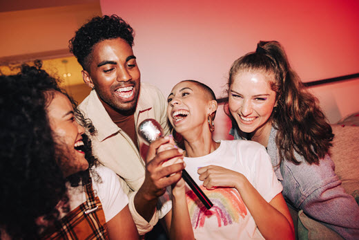 diverse group of teen friends laughing and smiling while passing the mic at a party
