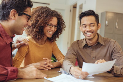 three adults working together looking at paper smiling