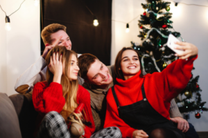 teen friends talking a selfie inside on couch in front of a christmas tree