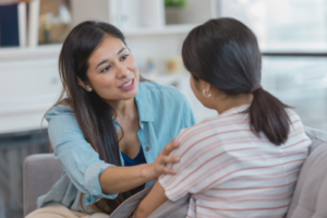 A caring mother attentively listens and offers support to her teenage daughter during a heartfelt conversation at home.